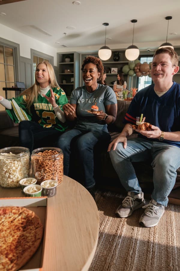 Friends eating pizza on a couch